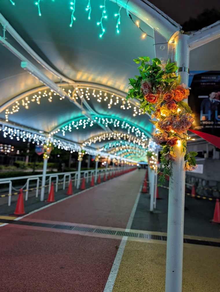 HANSHIN URBAN KEIBAのファン通路を彩るアクアグリーンとゴールドのアイシクルライト、柱のフラワー装飾